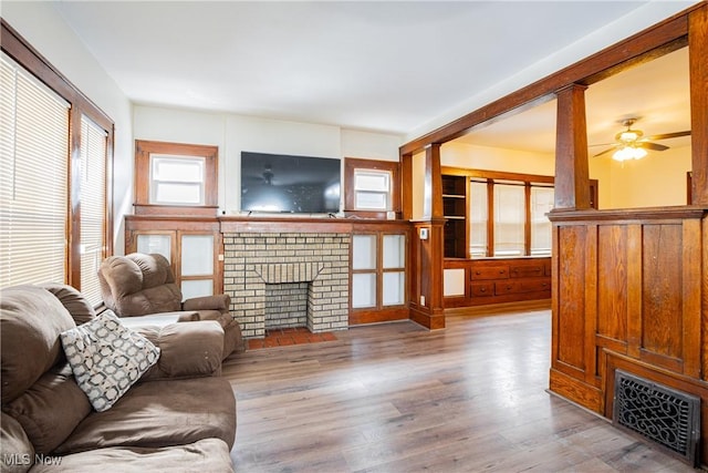 living room with ceiling fan, a fireplace, and light hardwood / wood-style flooring