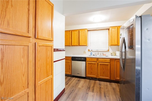 kitchen featuring hardwood / wood-style flooring, stainless steel appliances, sink, and decorative backsplash