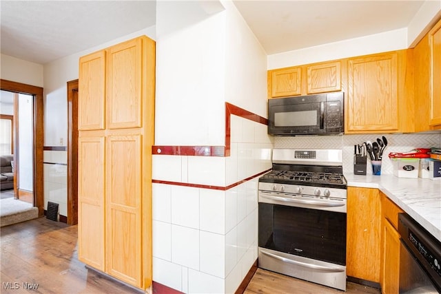 kitchen with tile walls, light hardwood / wood-style flooring, and black appliances