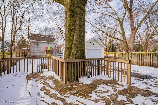 snow covered deck featuring a garage and an outbuilding