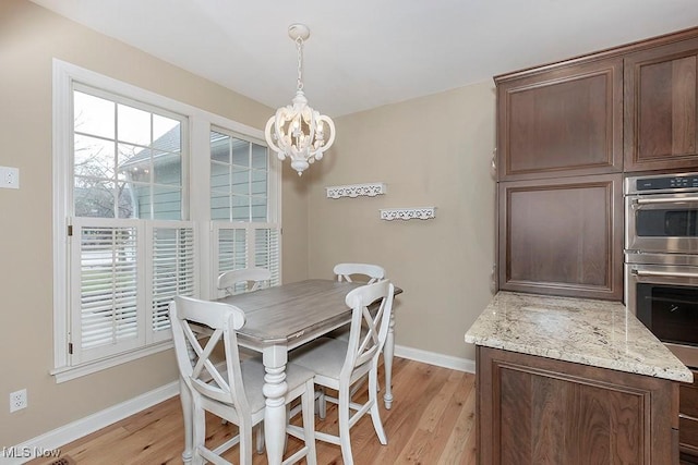 dining room with a healthy amount of sunlight, a chandelier, and light wood-type flooring