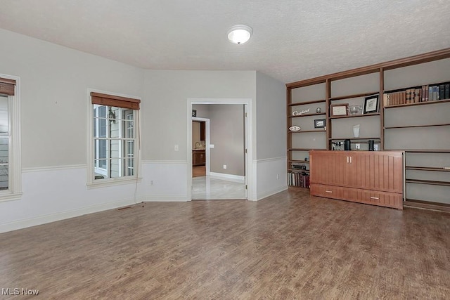 unfurnished living room featuring hardwood / wood-style flooring and a textured ceiling