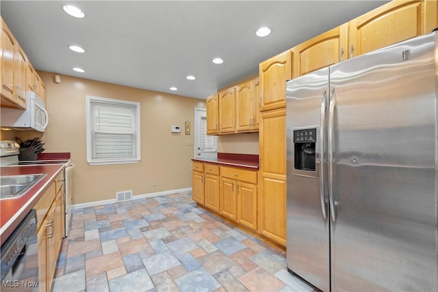 kitchen featuring light brown cabinetry, range, dishwasher, and stainless steel refrigerator with ice dispenser