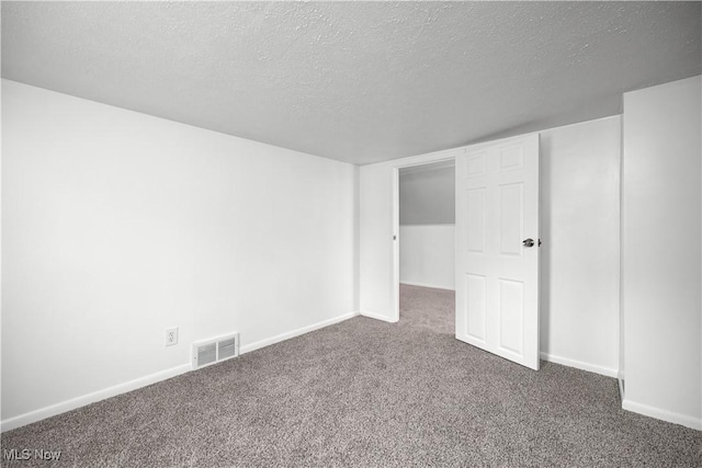 interior space featuring dark colored carpet and a textured ceiling