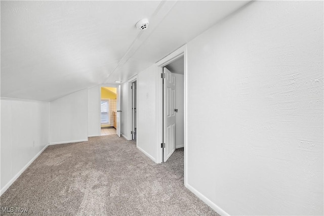 additional living space featuring vaulted ceiling and light carpet