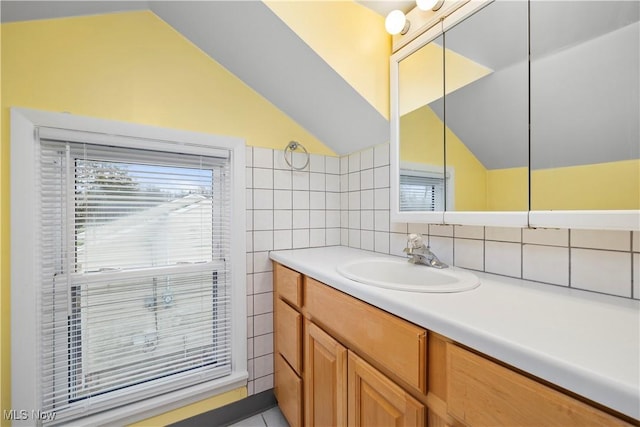 bathroom featuring lofted ceiling, tile walls, vanity, and plenty of natural light