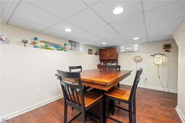 dining room featuring dark hardwood / wood-style floors and a drop ceiling