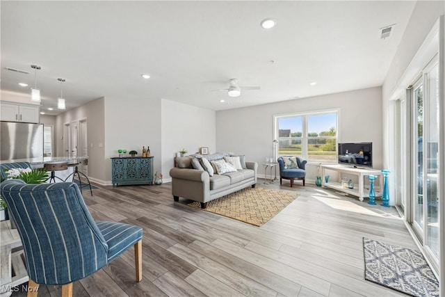 living room with ceiling fan and light hardwood / wood-style flooring