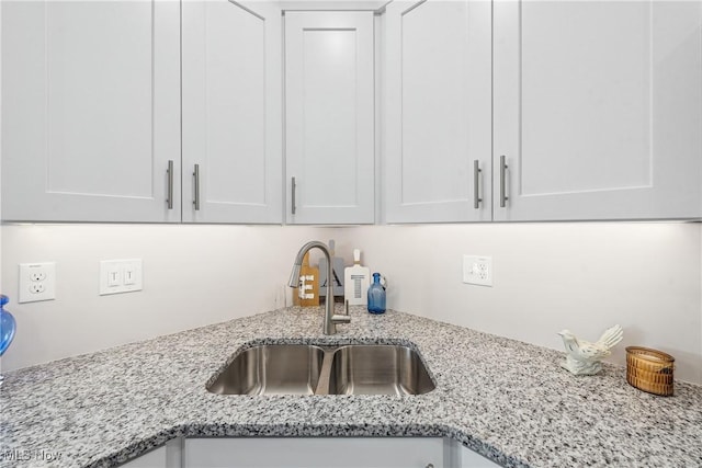 kitchen featuring sink, white cabinets, and light stone counters