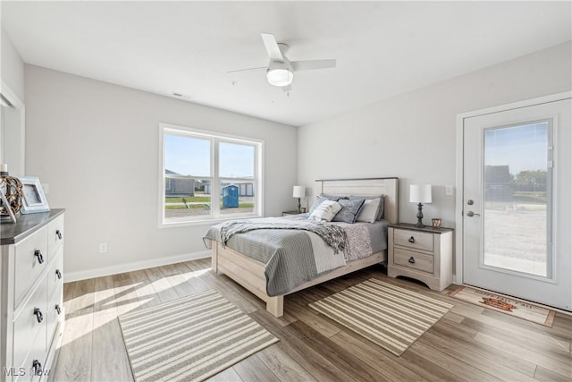 bedroom featuring ceiling fan, access to outside, multiple windows, and light wood-type flooring