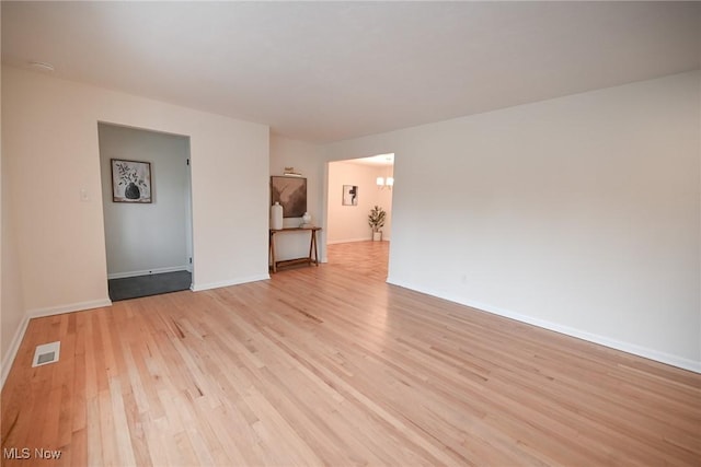 empty room featuring light hardwood / wood-style flooring and a chandelier