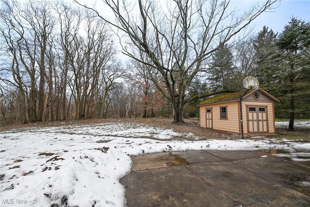 snowy yard featuring a storage shed