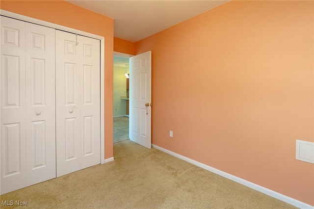 unfurnished bedroom featuring light colored carpet and a closet