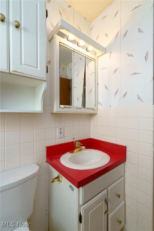 bathroom featuring vanity, tile walls, and toilet