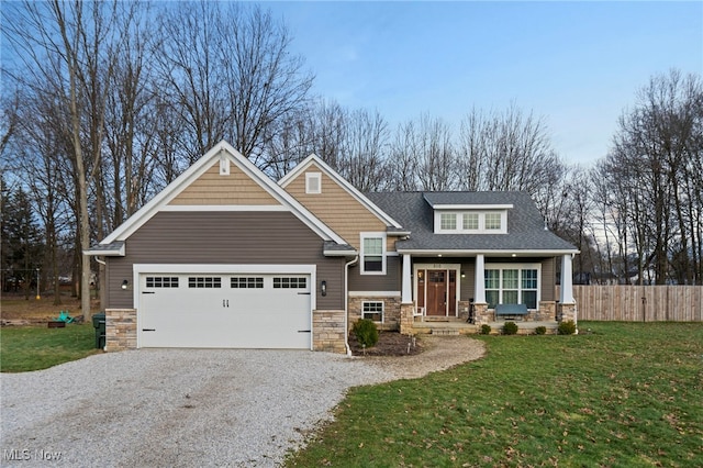 craftsman inspired home with a garage, a front lawn, and covered porch