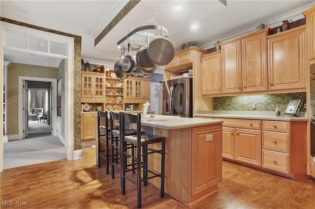 kitchen featuring a breakfast bar, stainless steel fridge with ice dispenser, a kitchen island with sink, and light brown cabinets