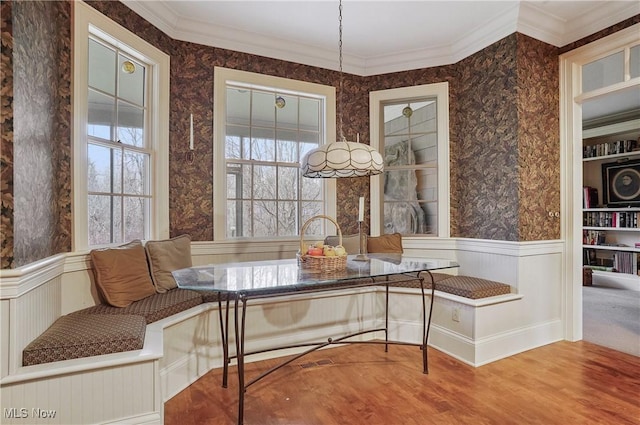 dining space with breakfast area, wood-type flooring, and ornamental molding