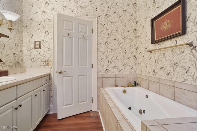 bathroom featuring wood-type flooring, vanity, and tiled tub