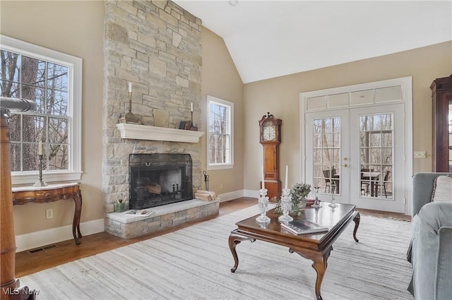 living room with lofted ceiling, a fireplace, light hardwood / wood-style floors, and french doors