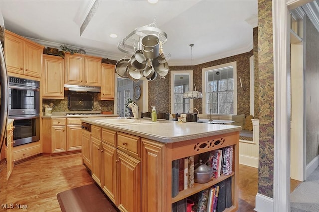 kitchen with a kitchen island with sink, sink, double oven, and light brown cabinets