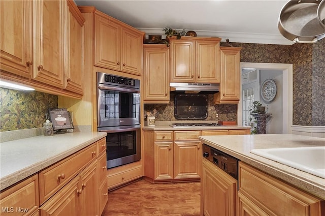 kitchen with ornamental molding, appliances with stainless steel finishes, decorative backsplash, and light hardwood / wood-style flooring