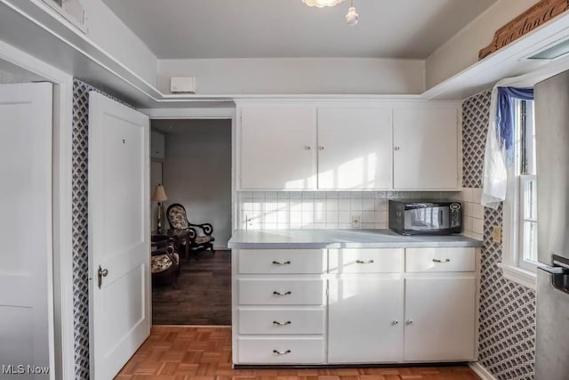 kitchen with light parquet floors, white cabinets, and decorative backsplash