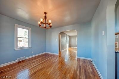 empty room featuring a notable chandelier and hardwood / wood-style floors