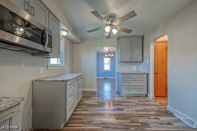 kitchen featuring ceiling fan, light stone countertops, light hardwood / wood-style flooring, and gray cabinetry