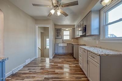 kitchen featuring sink, gray cabinets, ceiling fan, dark hardwood / wood-style floors, and light stone countertops