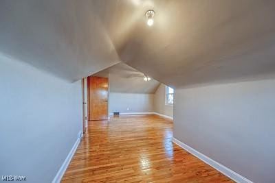 bonus room with vaulted ceiling and light wood-type flooring