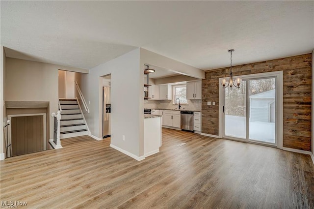 unfurnished living room with sink, a notable chandelier, and light hardwood / wood-style flooring