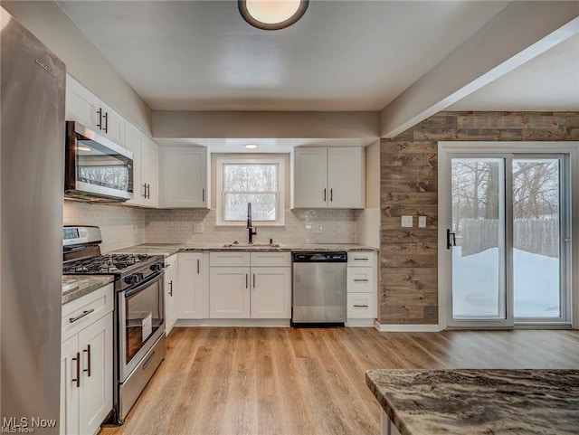 kitchen featuring white cabinetry, sink, stainless steel appliances, and light stone countertops