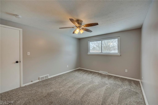 carpeted spare room featuring ceiling fan and a textured ceiling