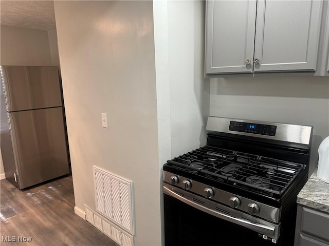 kitchen featuring stainless steel appliances, gray cabinets, hardwood / wood-style floors, and light stone counters