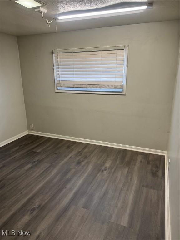 unfurnished room with a textured ceiling and dark hardwood / wood-style flooring