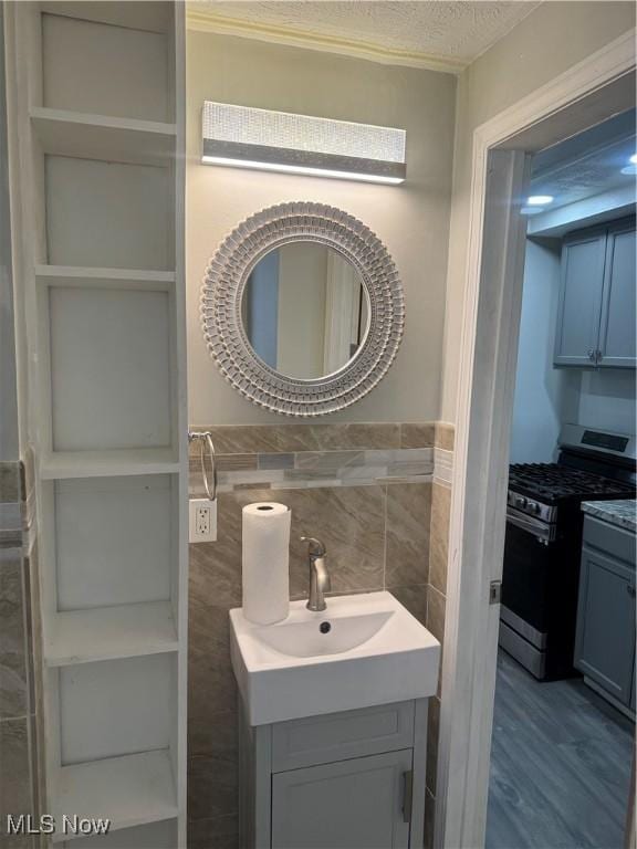 bathroom with hardwood / wood-style flooring, vanity, tile walls, and a textured ceiling