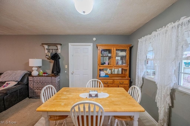 dining space with light colored carpet and a textured ceiling