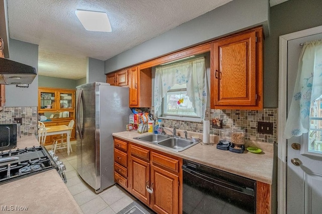 kitchen featuring light tile patterned flooring, appliances with stainless steel finishes, tasteful backsplash, sink, and a textured ceiling