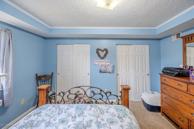 bedroom with multiple closets, light colored carpet, and a textured ceiling