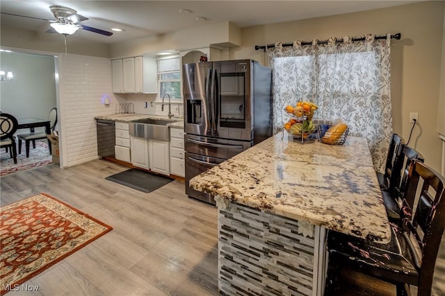 kitchen featuring sink, light hardwood / wood-style flooring, white cabinetry, light stone counters, and stainless steel fridge with ice dispenser