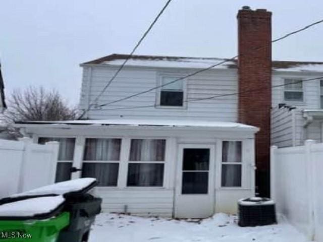 snow covered back of property featuring cooling unit