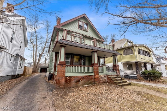 view of front of home featuring a porch, a balcony, a garage, and an outdoor structure