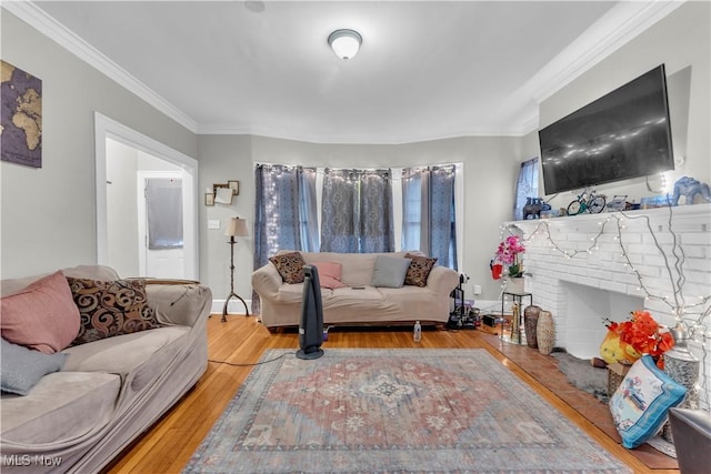 living room with a brick fireplace, crown molding, and wood-type flooring