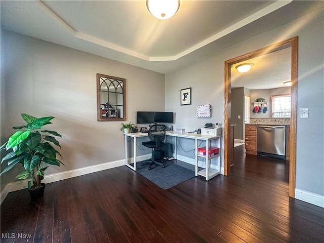 home office with dark wood-type flooring and a tray ceiling