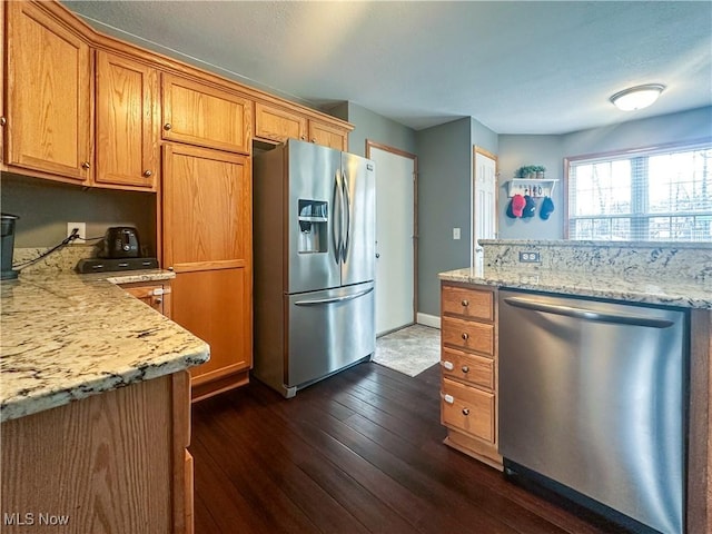 kitchen featuring stainless steel appliances, dark wood-type flooring, baseboards, brown cabinets, and light stone countertops