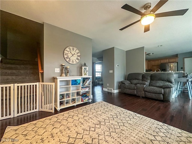 living area with a ceiling fan, visible vents, baseboards, and hardwood / wood-style flooring