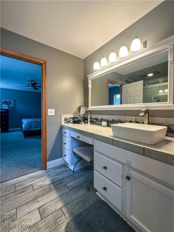 bathroom featuring ceiling fan, a shower with shower door, vanity, baseboards, and wood tiled floor