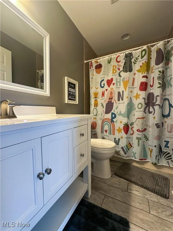 full bath with toilet, a shower with shower curtain, and vanity