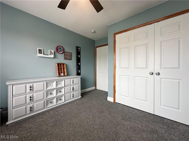 unfurnished bedroom featuring dark colored carpet, a closet, ceiling fan, and baseboards