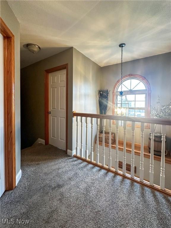 corridor featuring baseboards and carpet flooring